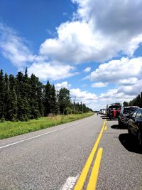 Road by trees against sky