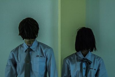 Portrait of young man standing against wall