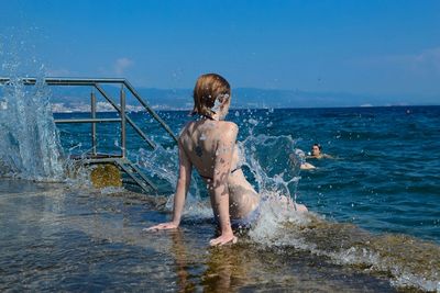 Woman standing by sea against sky