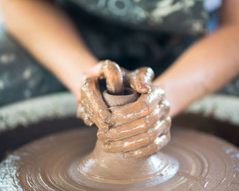 Midsection of woman making pot on pottery wheel