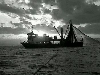 Boats in sea against cloudy sky