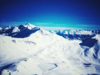 Scenic view of snowcapped mountains against blue sky