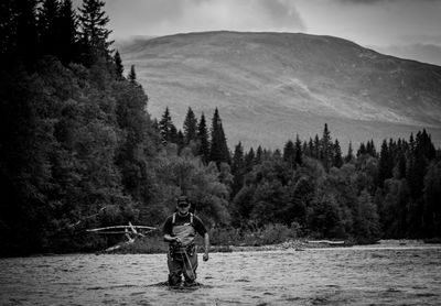 Man standing in lake against mountain