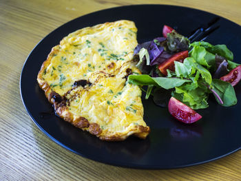 Close-up of fried omelet with salad in plate on table