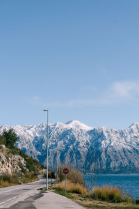 Road by snowcapped mountains against sky