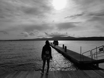 View of woman standing on pier looking out to sea
