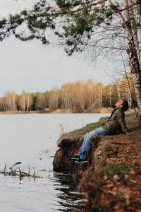 Young man sitting on the ground at forest in autumn