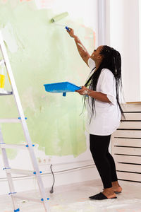 Side view of woman standing against wall at home