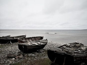 Abandoned boat moored on beach against sky