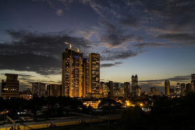 Illuminated buildings in city against sky at dusk