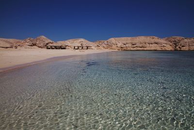 Scenic view of beach against clear blue sky