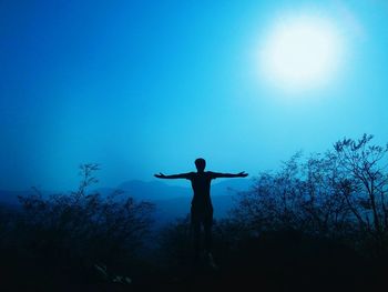 Low angle view of silhouette person against blue sky