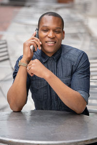 Portrait of smiling man holding while sitting on table