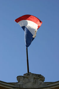 Low angle view of french flag  against clear blue sky in a windy day