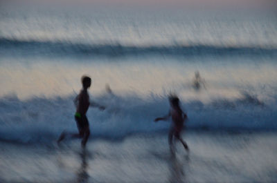 Blurred motion of man and woman running on beach