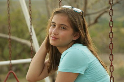 Teenage girl sitting on swing at playground