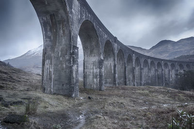 Arch bridge against cloudy sky