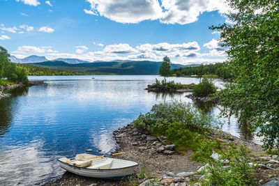 Rowing boat parked by a lake located in fatmomakke in northern sweden with mountains in the distance