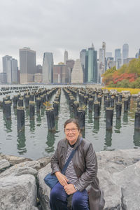 Low angle view of man sitting on rock in city