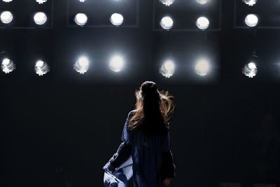 Rear view of woman standing against illuminated lights