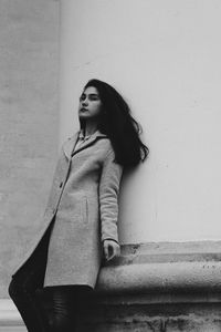 Portrait of young woman standing against wall