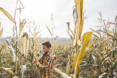 Boy standing on field against sky