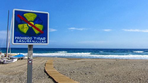 Information sign on beach against sky