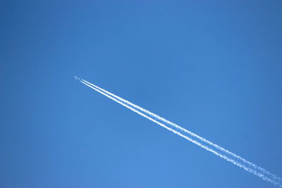 Low angle view of vapor trail against blue sky