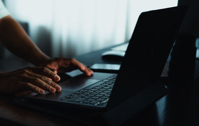 Cropped hands using laptop on table