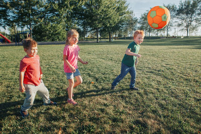 Children playing with ball on grassy land in park