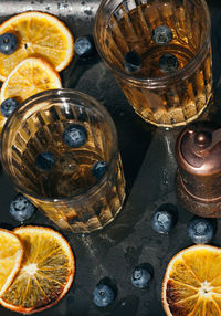 Lemonade in glasses decorated with blueberries and dry orange on black background