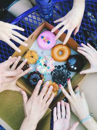 Cropped hand reaching towards donuts