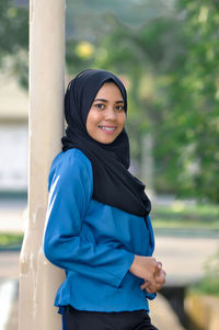 Portrait of young woman standing against sky