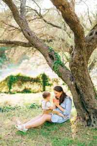 Mother playing with daughter near tree