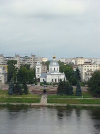 Buildings at waterfront against cloudy sky