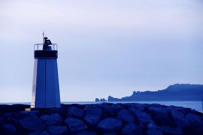 Lighthouse by sea against sky