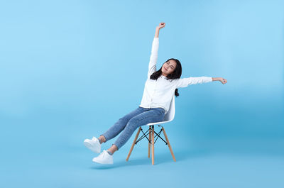 Full length of young woman against blue background
