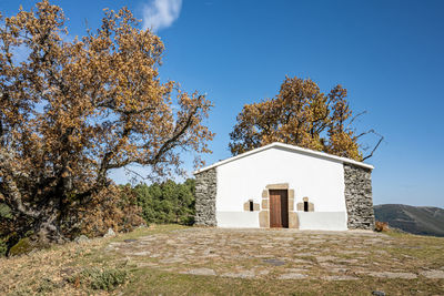 House on field against clear blue sky