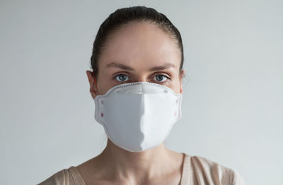 Portrait of woman wearing mask against wall