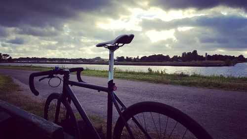 Bicycle by river against sky