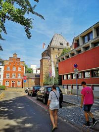 Rear view of people walking on street amidst buildings in city
