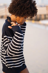 Young black woman standing by the sea wearing striped jumper