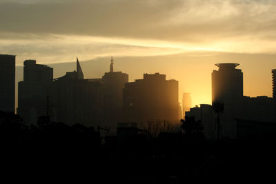 Silhouette buildings against sky during dawn
