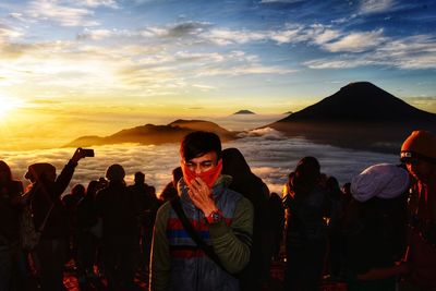 People standing on beach against sky during sunset