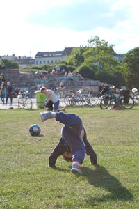 Boy playing soccer on field against sky