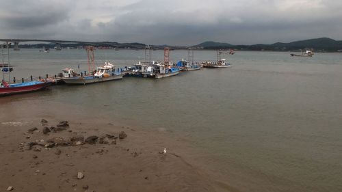 Boats in sea against cloudy sky