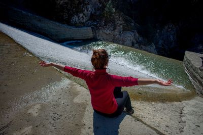 Rear view of woman with arms outstretched in water