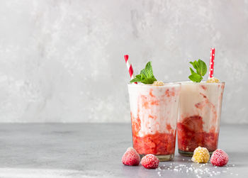 Layered strawberry and raspberry smoothie or milkshake with mint, raspberry and coconut flakes. 