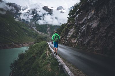 Rear view of man walking on road against mountains