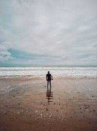 Rear view of woman on beach against sky